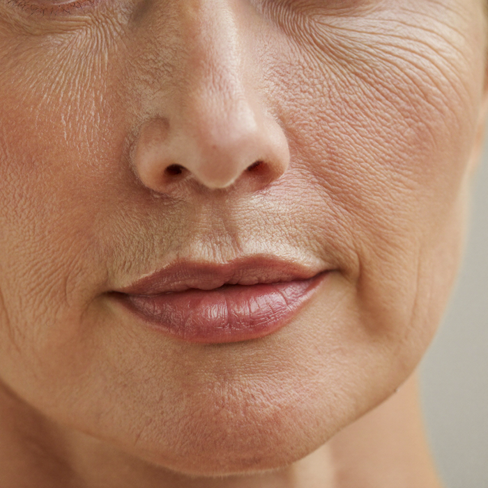 Close-up of the cheek and mouth of a woman in her fifties, refined skin texture