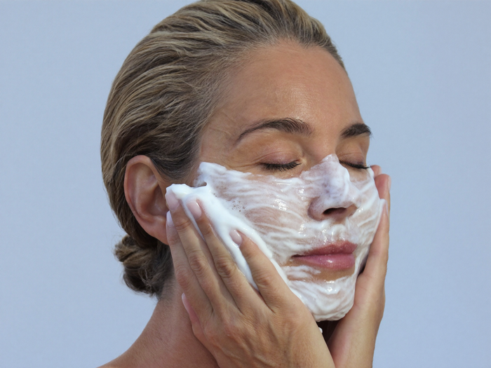 Woman in her fifties cleansing her face with white foam