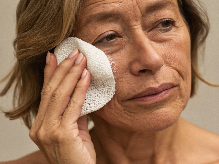 Woman in her fifties sweeping an exfoliating pad across her cheek
