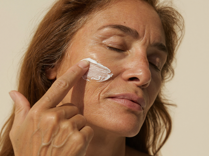 Woman in her fifties smoothing cream across her cheekbone